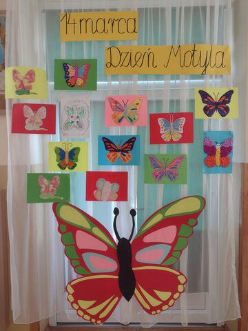  na tablicy wywieszone są prace dzieci przedstawiające motyle, na dole duży kolorowy motyl
