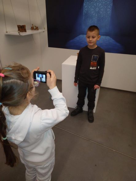 uczeń fotografuje ucznia na tle wystawy